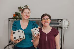 Liz Yntema and Rachelle Provost smiling while holding dice